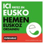 logo carré de EUSKO la monnaie locale du Pays basque. Texte en français en blanc sur fond vert clair Ici payez en Eusko. En noir en basque Hemen Euskoz ordaindu. et une bande rouge en dessous indiquant en blanc le site www.euskalmoneta.org